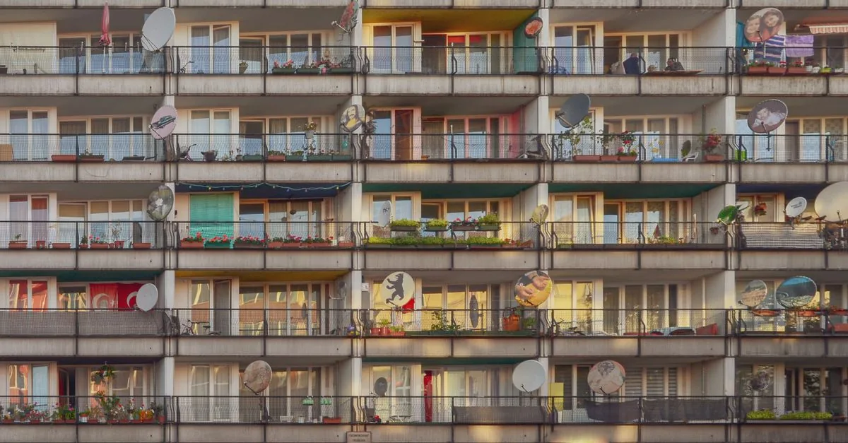 Photograph of a residential building with colorful balconies and satellite dishes in Berlin.